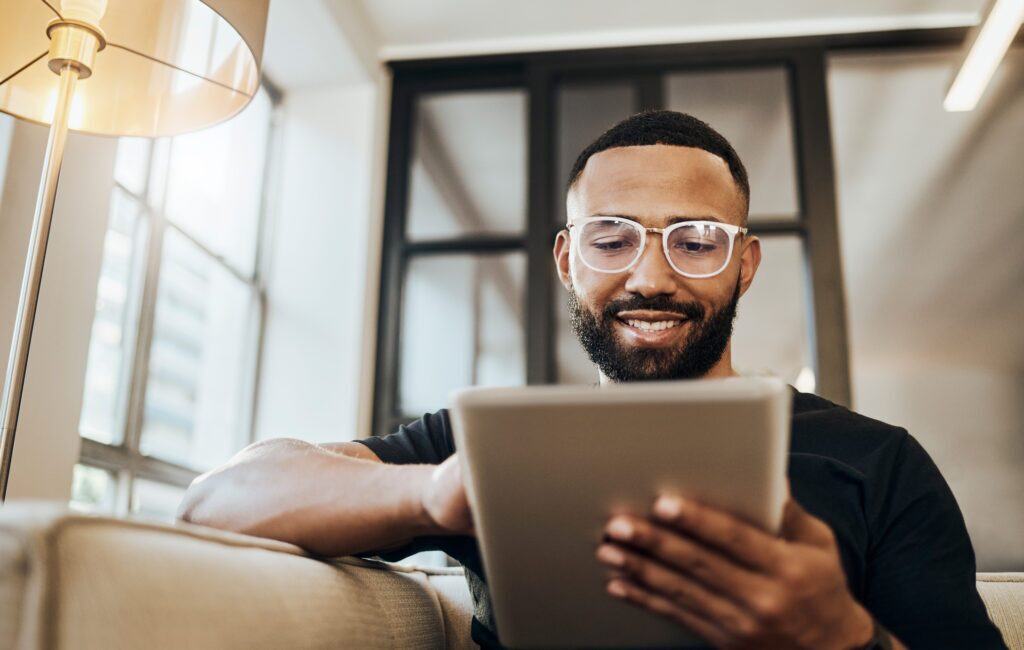 a man wearing glasses is smiling while using a tablet