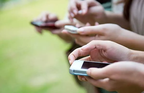 row of hands using mobile phones