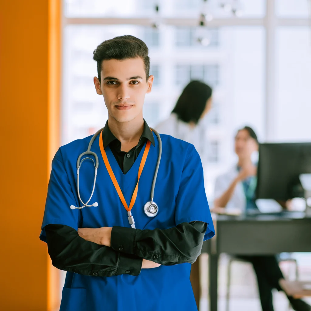 A photo of a male healthcare worker standing, an office interior behind him.