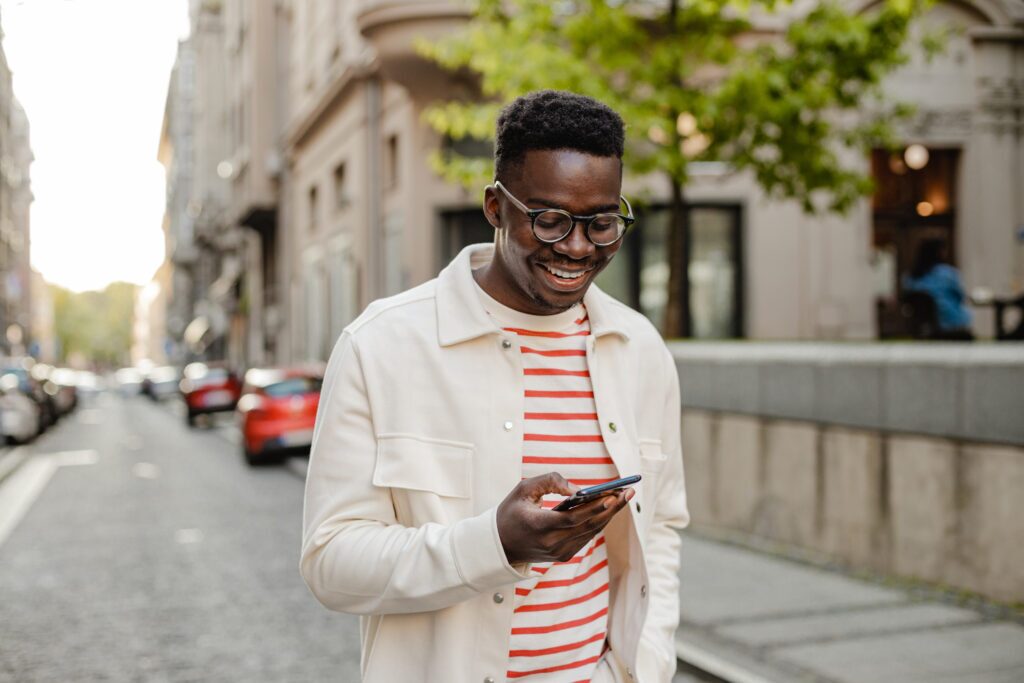 Man wearing white jacket walking on city road holding phone