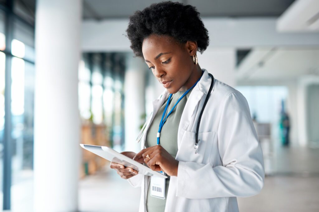 a woman in a lab coat looks at a tablet