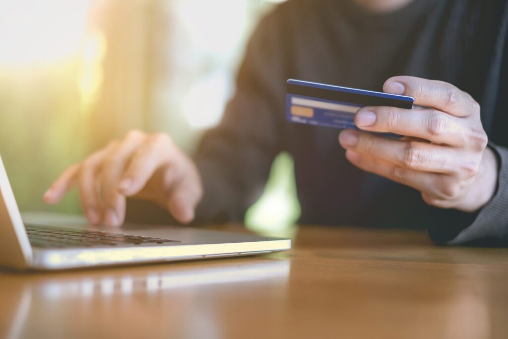 a person holding a credit card in front of a laptop