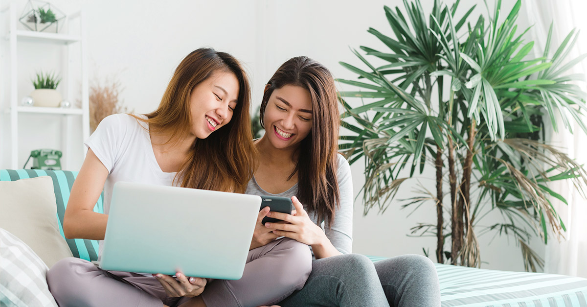 two girls laughing and browsing on mobile devices