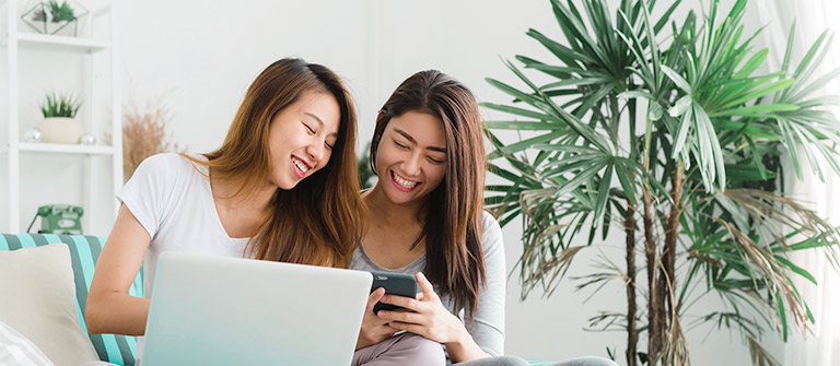 two girls laughing and browsing on mobile devices